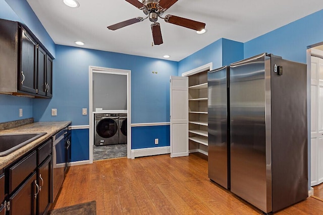 kitchen with baseboards, appliances with stainless steel finishes, hardwood / wood-style flooring, and washer and dryer