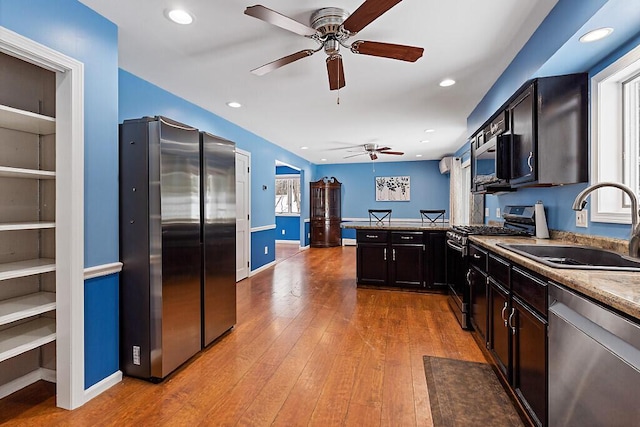 kitchen with recessed lighting, appliances with stainless steel finishes, a sink, a peninsula, and hardwood / wood-style flooring