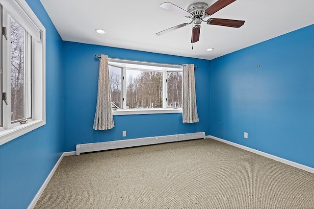 unfurnished room with a baseboard heating unit, carpet, ceiling fan, and baseboards