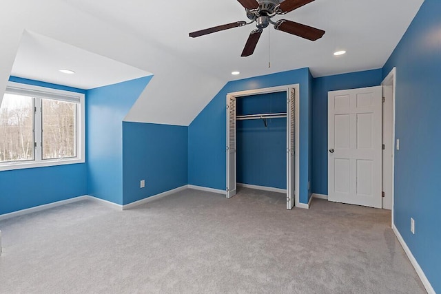 unfurnished bedroom with carpet flooring, a ceiling fan, baseboards, vaulted ceiling, and a closet