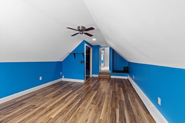 additional living space with baseboards, a ceiling fan, wood finished floors, vaulted ceiling, and baseboard heating