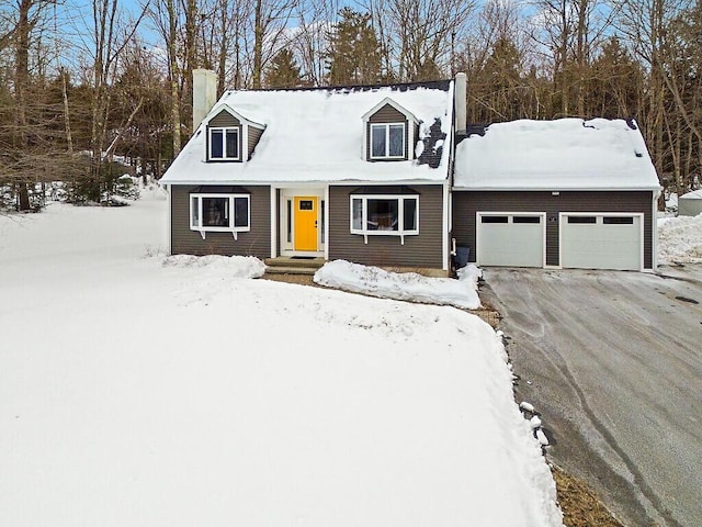 cape cod house with a garage, driveway, and a chimney