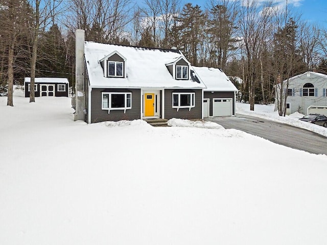 cape cod-style house featuring a garage, a chimney, and aphalt driveway