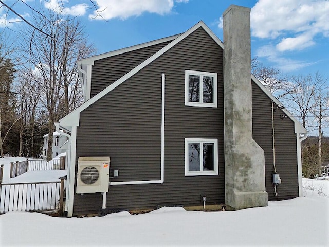 view of snowy exterior featuring ac unit, a chimney, and a deck