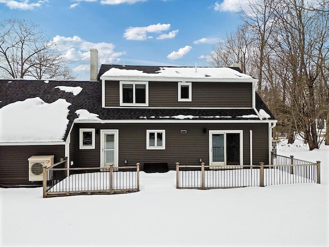 snow covered rear of property featuring roof with shingles, ac unit, and fence