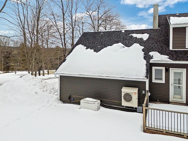 snow covered property with a shingled roof, ac unit, and a jacuzzi