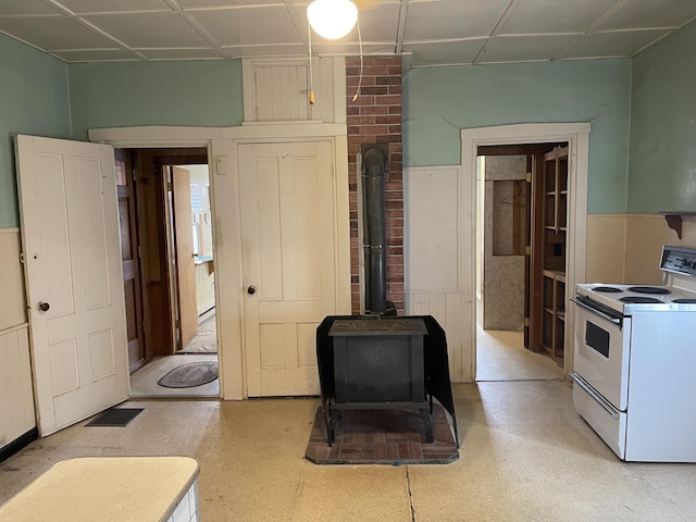 48 Gay St, Rockland, ME 04841 - kitchen featuring a wainscoted wall, light floors, white electric stove, and a wood stove