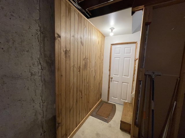 doorway to outside with wooden walls and unfinished concrete floors