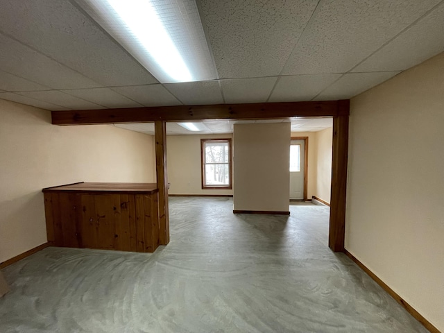 basement featuring a paneled ceiling and baseboards