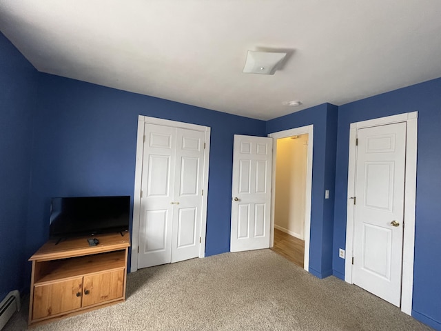 carpeted bedroom featuring a baseboard heating unit and a closet