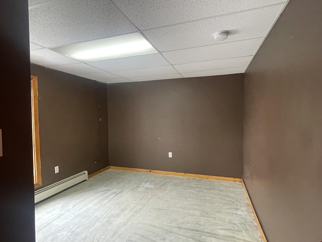 empty room with a baseboard heating unit, a paneled ceiling, and baseboards