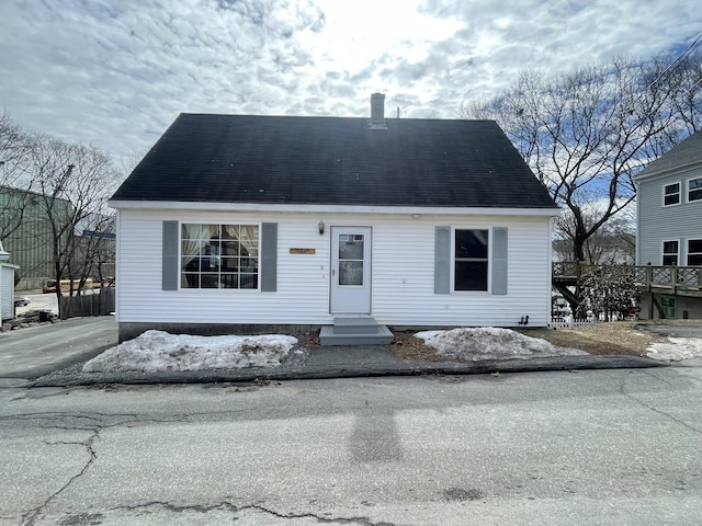 view of front of house with entry steps, roof with shingles, and a chimney