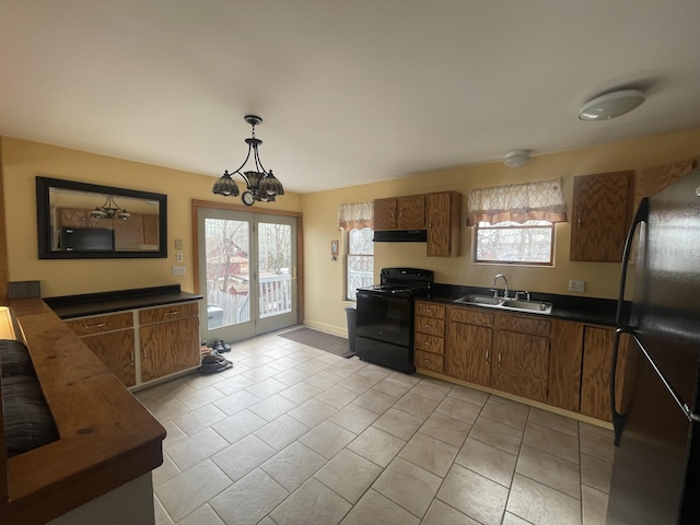 kitchen with black appliances, brown cabinetry, dark countertops, and a sink