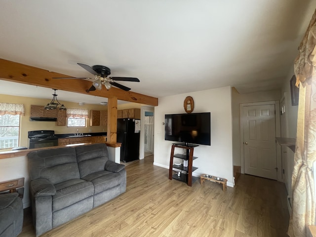 living area featuring baseboards, ceiling fan, and light wood finished floors