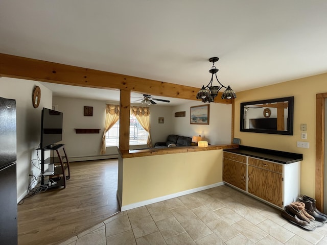 kitchen featuring ceiling fan, baseboards, open floor plan, beamed ceiling, and dark countertops