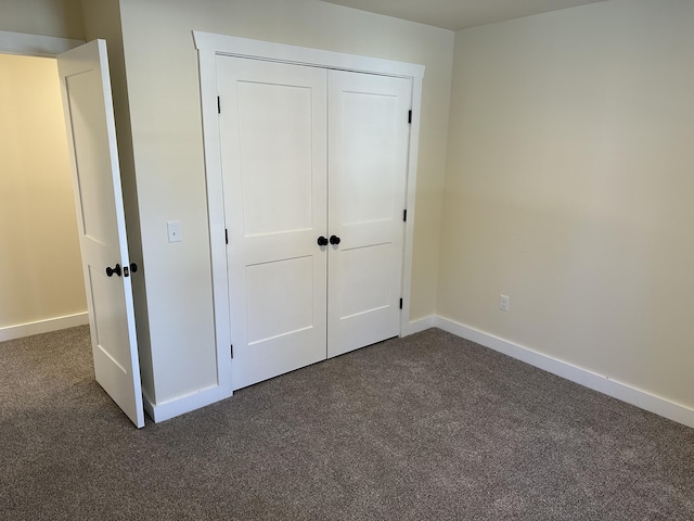 unfurnished bedroom featuring baseboards and dark colored carpet