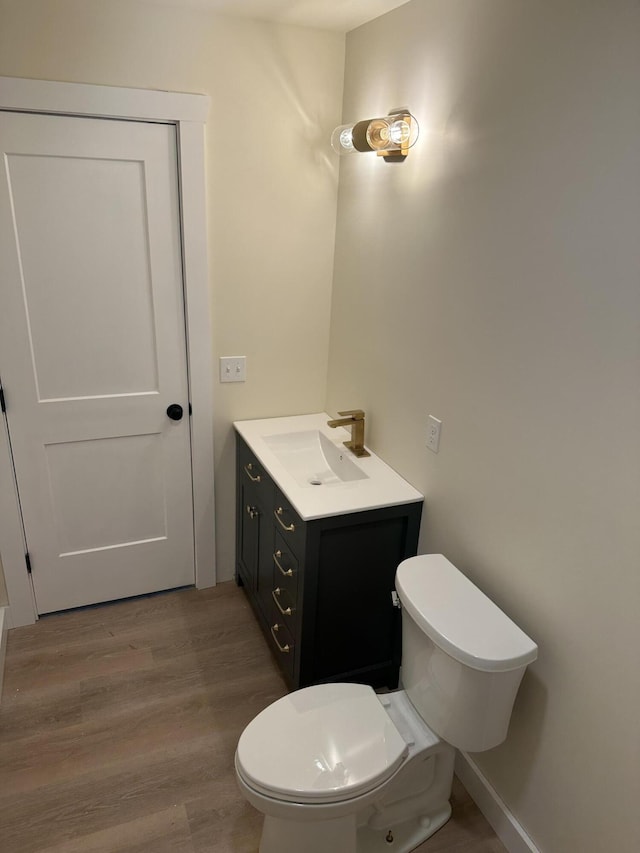 bathroom with vanity, wood finished floors, and toilet