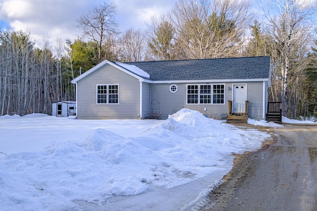 single story home with roof with shingles, an outdoor structure, and a shed