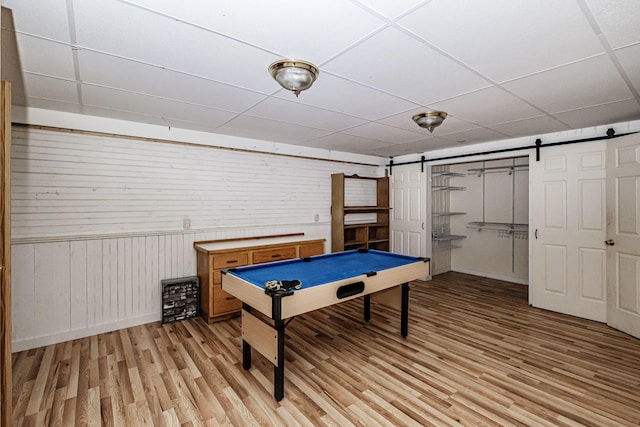 playroom featuring light wood-style floors, a barn door, billiards, and a drop ceiling