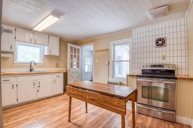 kitchen with light wood-type flooring, electric stove, light countertops, and a sink