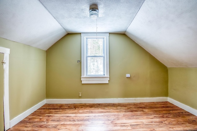 bonus room with baseboards, vaulted ceiling, a textured ceiling, and wood finished floors