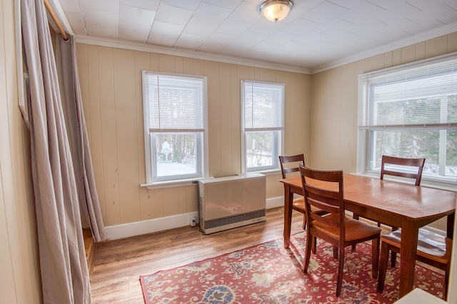 dining area featuring light wood-style floors, crown molding, and baseboards