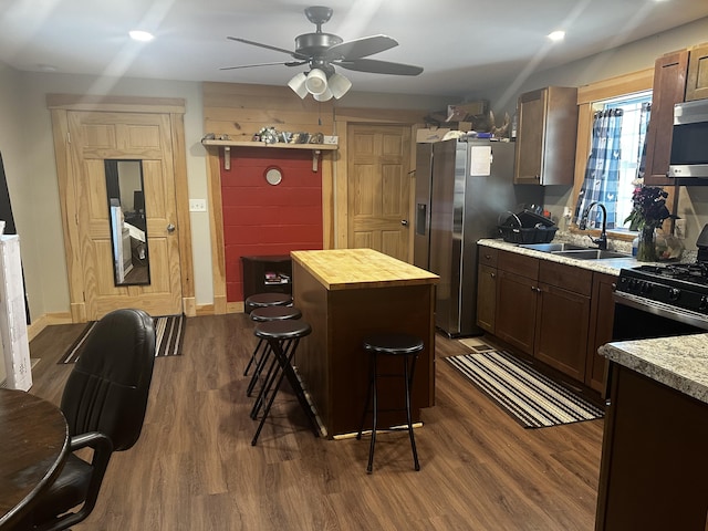 kitchen featuring stainless steel appliances, dark wood-style flooring, a sink, and wooden counters