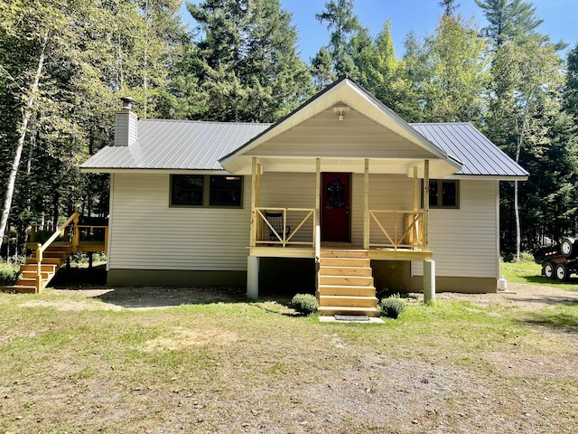 view of front of property with stairs, metal roof, a porch, and a chimney