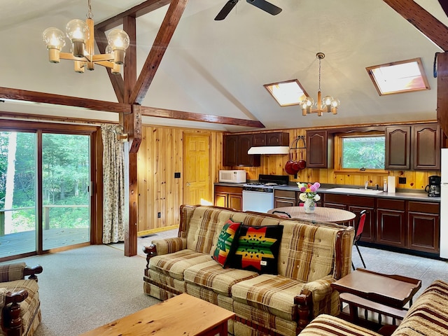 living room featuring light carpet, a skylight, wooden walls, high vaulted ceiling, and ceiling fan with notable chandelier