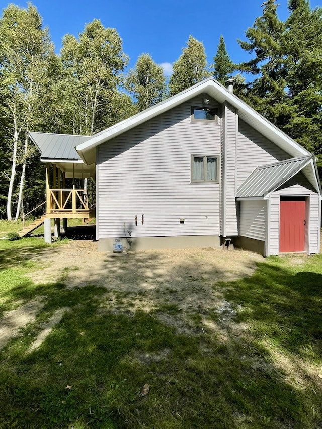 view of property exterior with an outbuilding, metal roof, a yard, and a storage shed