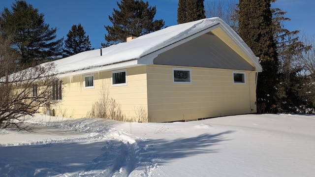 snow covered property with a chimney