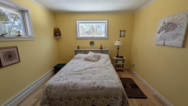 bedroom featuring a baseboard radiator, multiple windows, crown molding, and wood finished floors