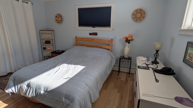 bedroom with baseboard heating and wood finished floors