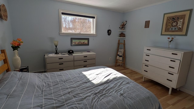 bedroom with baseboards, light wood-style flooring, and crown molding