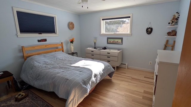 bedroom with light wood-style floors, baseboards, ornamental molding, and baseboard heating