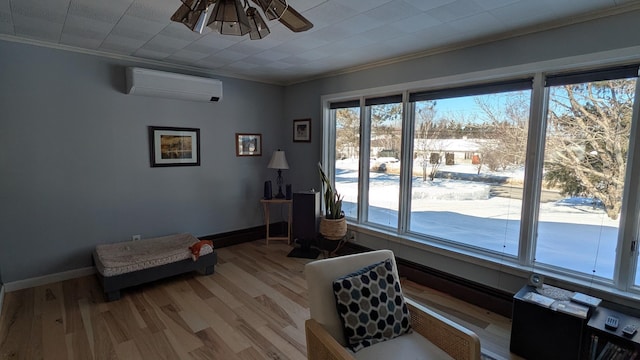 sitting room featuring light wood finished floors, crown molding, and a wall mounted air conditioner