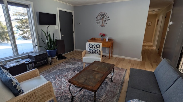 living room featuring a healthy amount of sunlight, baseboards, ornamental molding, and wood finished floors