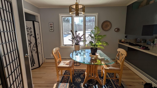 dining area with light wood-style floors, a baseboard radiator, a healthy amount of sunlight, and crown molding