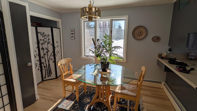 dining room featuring light wood-type flooring, an inviting chandelier, a baseboard heating unit, and crown molding