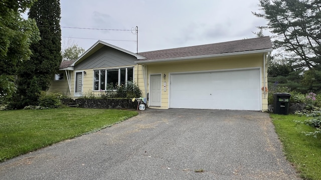 ranch-style home with aphalt driveway, a front yard, roof with shingles, and a garage