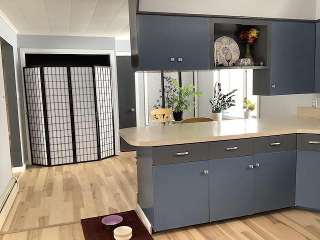 kitchen featuring light countertops, baseboard heating, a peninsula, and light wood-style flooring