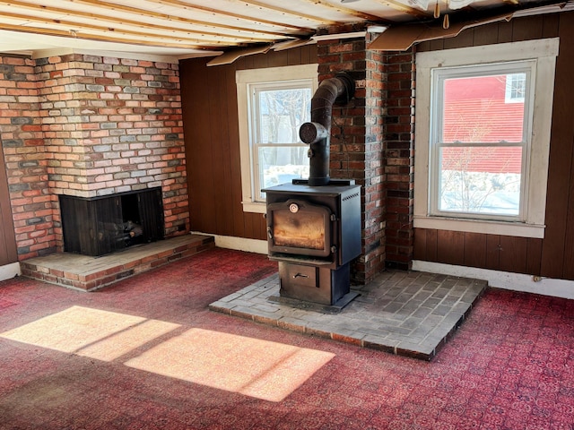 living area with carpet, a wood stove, wood walls, and a brick fireplace