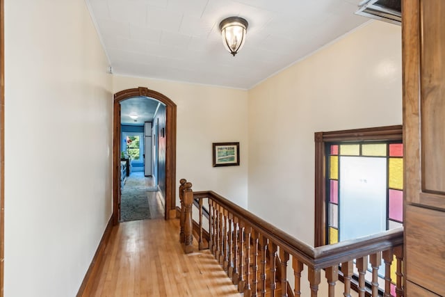 corridor featuring arched walkways, an upstairs landing, and wood finished floors