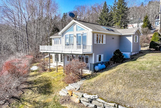 back of property with a deck, a lawn, and roof with shingles