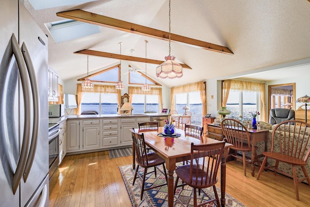 dining room with a textured ceiling, vaulted ceiling with beams, and light wood-style floors