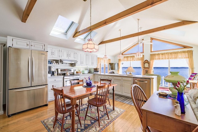 dining area featuring a skylight, beamed ceiling, light wood finished floors, and high vaulted ceiling