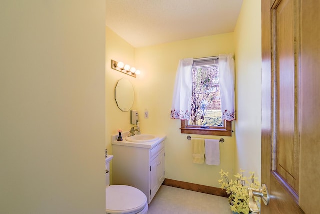 half bath featuring baseboards, toilet, and vanity