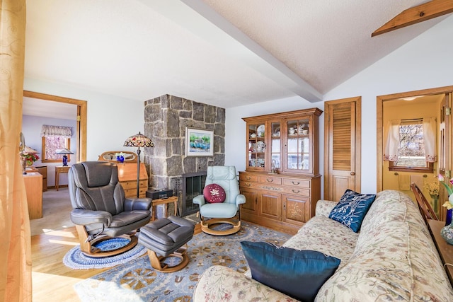 living room featuring a fireplace, vaulted ceiling with beams, a textured ceiling, and wood finished floors