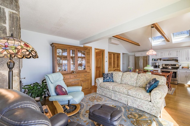 living room featuring lofted ceiling with skylight, a textured ceiling, and light wood-style flooring