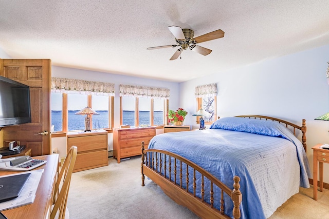 bedroom with a baseboard radiator, ceiling fan, a water view, a textured ceiling, and light carpet